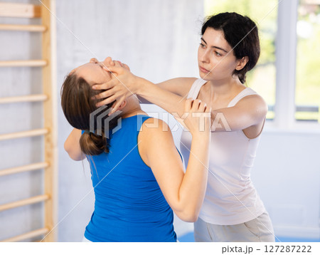 Woman and trainer train painful hold on self-defense course in boxing gym Woman and trainer train painful hold on self-defense course in boxing gym 127287222