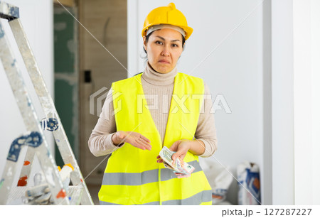 Female repairer holding cash and dissapointed by her wage Female repairer holding cash and dissapointed by her wage 127287227