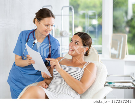 Adult female doctor shows contract to patient Adult female doctor shows contract to patient 127287245