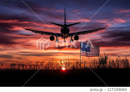Silhouette of a passenger plane at sunrise or sunset over the US flag. 127289069