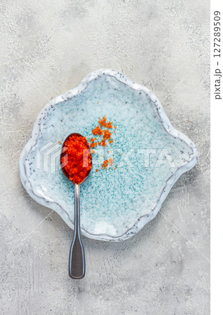 a spoon with orange flying fish caviar, Tobiko, on a light blue plate, caviar for rolls and sushi, close-up, a spoon with orange flying fish caviar, Tobiko, on a light blue plate, caviar for rolls and sushi, close-up, 127289509