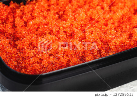 container with orange caviar, flying fish, Tobiko, on the table, caviar for rolls and sushi, close-up, 127289513