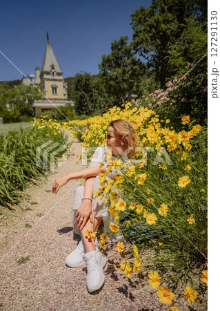 A woman is sitting in a field of yellow flowers A woman is sitting in a field of yellow flowers 127291130