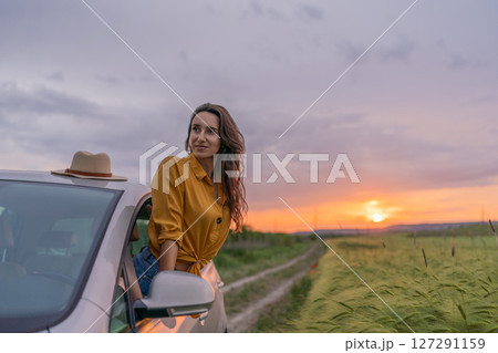 A woman in a yellow shirt is sitting in a car with a hat on 127291159