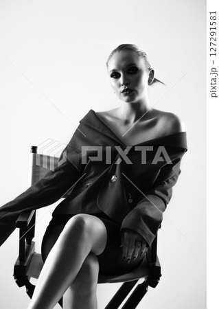 Beautiful woman black and white portrait with jacket and mini shirt sitting in high chair Beautiful woman black and white portrait with jacket and mini shirt sitting in high chair 127291581