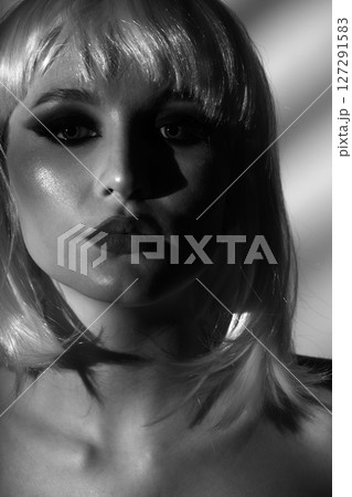 Beautiful woman with white wig illuminated by bright light through blinds 127291583