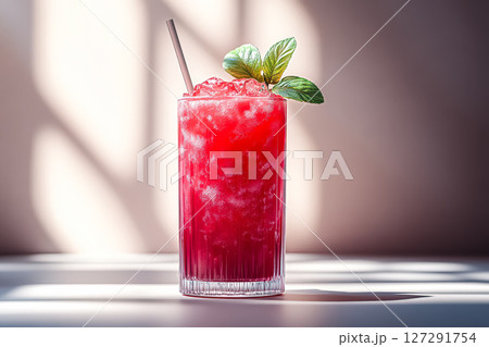Glass of red drink with a green leaf on top 127291754