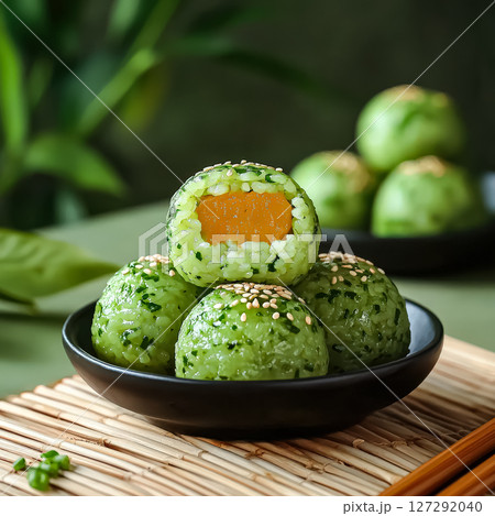 Bowl of green rice balls with one of them cut in half 127292040