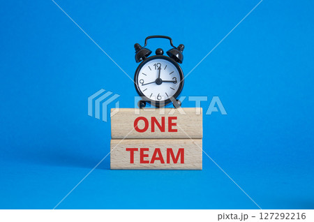 One Team symbol. Concept word One Team on wooden blocks. Beautiful blue background with alarm clock. Business and One Team concept. Copy space 127292216