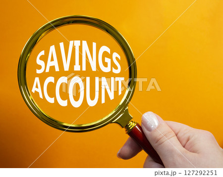 Savings Account symbol. Magnifying Glass with Concept word Savings Account. Businessman hand. Beautiful orange background. Business and Savings Account concept. Copy space Savings Account symbol. Magnifying Glass with Concept word Savings Account. Businessman hand. Beautiful orange background. Business and Savings Account concept. Copy space 127292251