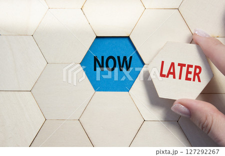 Now vs Later symbol. Concept word Now vs Later on wooden comb puzzle. Businessman hand. Beautiful blue background. Business and Now vs Later concept. Copy space 127292267