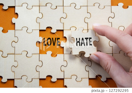 Love vs Hate symbol. Concept word Love vs Hate on wooden puzzle. Businessman hand. Beautiful orange background. Business and Love vs Hate concept. Copy space Love vs Hate symbol. Concept word Love vs Hate on wooden puzzle. Businessman hand. Beautiful orange background. Business and Love vs Hate concept. Copy space 127292295