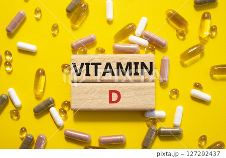 Vitamin D symbol. Concept word Vitamin D on wooden blocks. Beautiful yellow background with pills. Medicine and Vitamin D concept. Copy space Vitamin D symbol. Concept word Vitamin D on wooden blocks. Beautiful yellow background with pills. Medicine and Vitamin D concept. Copy space 127292437