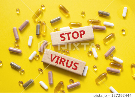 Stop Virus symbol. Concept word Stop Virus on wooden blocks. Beautiful yellow background with pills. Medicine and Stop Virus concept. Copy space Stop Virus symbol. Concept word Stop Virus on wooden blocks. Beautiful yellow background with pills. Medicine and Stop Virus concept. Copy space 127292444