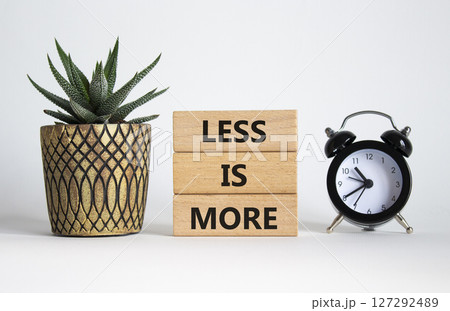 Less is More symbol. Concept words Less is More on wooden blocks. Beautiful white background with succulent plant and alarm clock. Business and Less is More concept. Copy space. 127292489