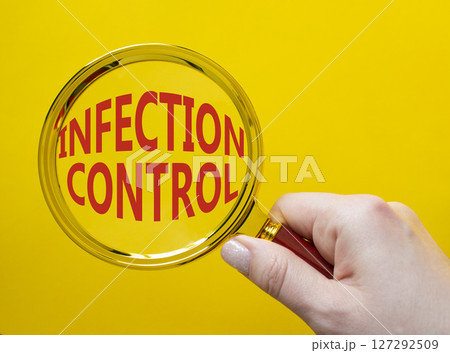 Infection Control symbol. Magnifying Glass with Concept word Infection Control. Businessman hand. Beautiful yellow background. Business and Infection Control concept. Copy space 127292509