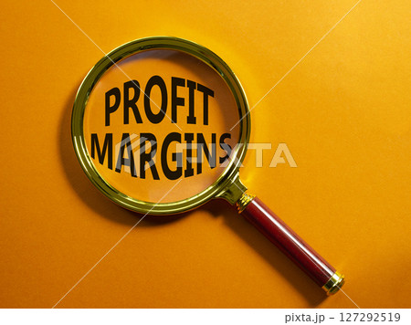 Profit Margins symbol. Magnifying glass with words Profit Margins. Beautiful orange background. Business and Profit Margins concept. Copy space. Profit Margins symbol. Magnifying glass with words Profit Margins. Beautiful orange background. Business and Profit Margins concept. Copy space. 127292519