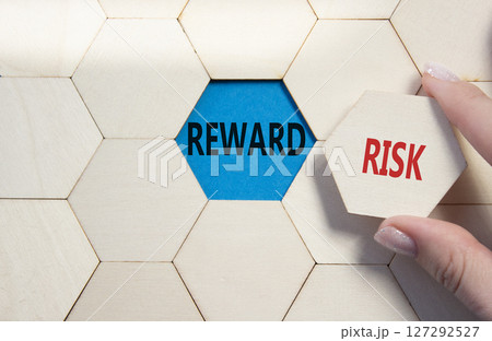 Risk or Reward symbol. Concept word Risk or Reward on wooden comb puzzle. Businessman hand. Beautiful blue background. Business and Risk or Reward concept. Copy space Risk or Reward symbol. Concept word Risk or Reward on wooden comb puzzle. Businessman hand. Beautiful blue background. Business and Risk or Reward concept. Copy space 127292527