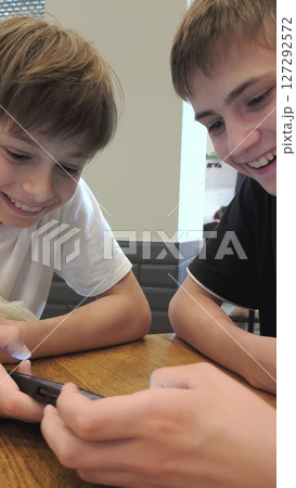 High school students teens gen z two gue, friends playing online video game e-sport play diverse gadgets. Guys playing on the phone. 127292572