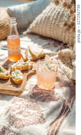Natural daylight picnic setup with spritz cocktail and artisan crostini, laid-back mood, rustic textiles, outdoor brunch vibe, eco-friendly styling 127292730