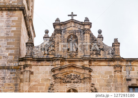 Carved stone sculpture of a figure surrounded by decorative elements on a historical building Carved stone sculpture of a figure surrounded by decorative elements on a historical building 127293180
