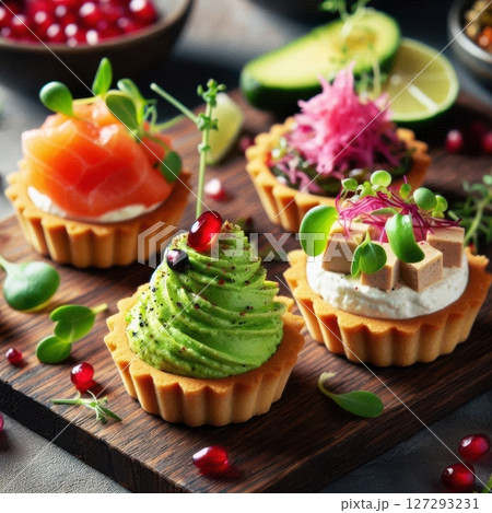 Sophisticated selection of bite-sized tartlets featuring bold flavors and modern garnishes, styled for upscale food photography and contemporary culinary trends. 127293231