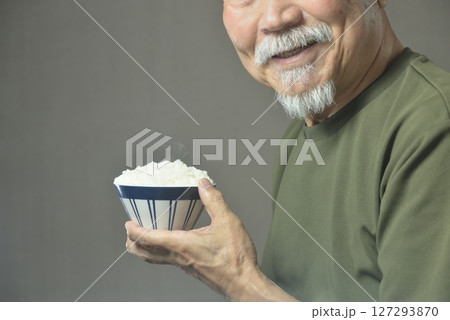 お茶碗で湯気の立ちのぽる温かいご飯を食べる老人 127293870