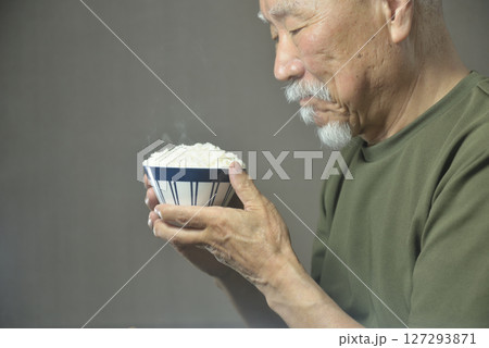 お茶碗で湯気の立ちのぽる温かいご飯を食べる老人 お茶碗で湯気の立ちのぽる温かいご飯を食べる老人 127293871