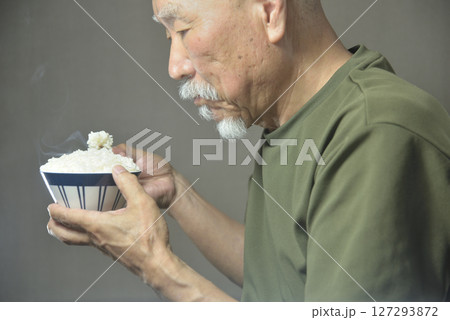お茶碗で湯気の立ちのぽる温かいご飯を食べる老人 お茶碗で湯気の立ちのぽる温かいご飯を食べる老人 127293872