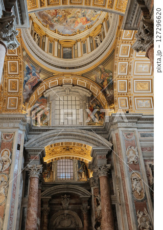 Ornate vaulted ceilings and central dome of Saint Peters Basilica in Vatican City richly decorated with golden details frescoes and religious architecture. High quality photo 127296620
