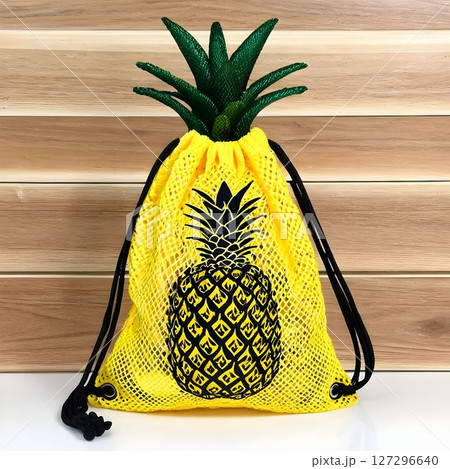 Colorful yellow pineapple-shaped bag displayed on a wooden background ideal for summer outings and beach activities 127296640