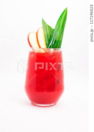 red apple cocktail with ice served in clear glass and garnished with tropical green leaves and apple slices on white background. High quality photo 127296828
