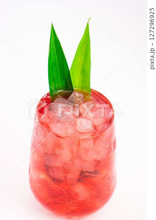 red berry cocktail served in clear glass with crushed ice and green tropical leaves isolated on white background. High quality photo 127296925