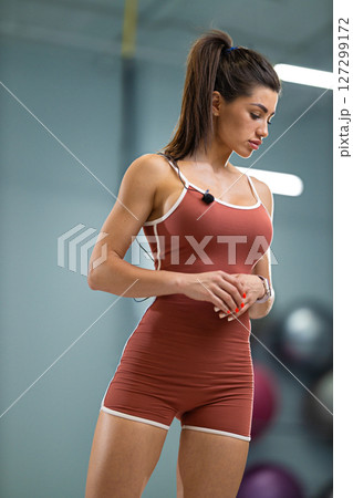 sporty girl announcer stands confidently in a contemporary fitness studio She is dressed in a fitted outfit, preparing to engage with an audience 127299172