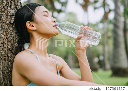 Young Asian woman in activewear sitting under a tree 127301367