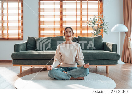 Happy young Asian woman practicing yoga and meditation at home 127301368