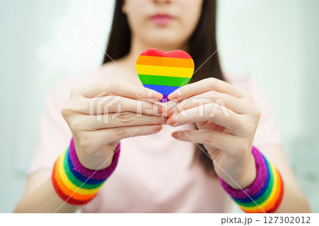 Asian woman holding LGBT heart with rainbow flag. 127302012
