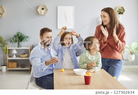 Young family with kids having fun together at home on weekend playing and throwing tennis balls Young family with kids having fun together at home on weekend playing and throwing tennis balls 127302634