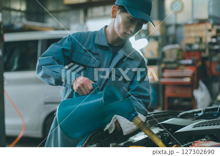 エンジンオイルを入れる自動車整備士 127302690