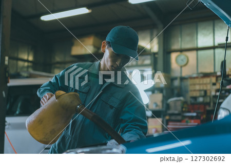 エンジンオイルを入れる自動車整備士 127302692