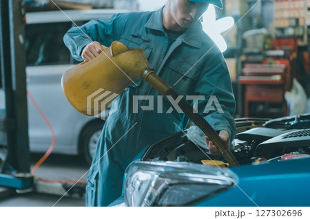 エンジンオイルを入れる自動車整備士 127302696