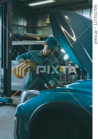 エンジンオイルを入れる自動車整備士 127302700