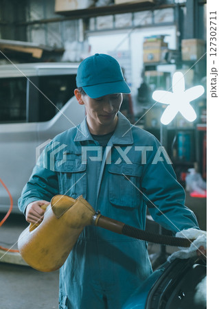 エンジンオイルを入れる自動車整備士 127302711