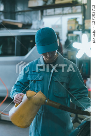 エンジンオイルを入れる自動車整備士 127302712