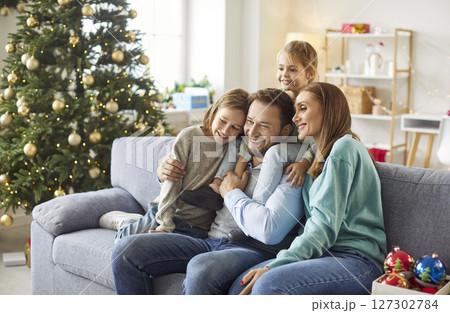 Happy family with children celebrate Christmas at home sitting on sofa in festive living room 127302784