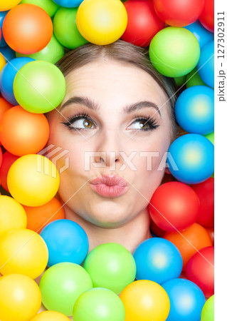 Beautiful woman close-up studio portrait in colorful balls background Beautiful woman close-up studio portrait in colorful balls background 127302911