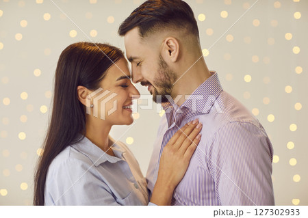 Portrait of a young happy affectionate couple standing with bokeh background Portrait of a young happy affectionate couple standing with bokeh background 127302933