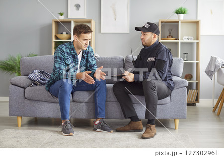Police officer is interviewing young man who has become victim of house burglary Police officer is interviewing young man who has become victim of house burglary 127302961
