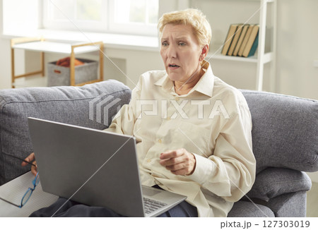 Frustrated desperate old woman reading bad news online at home, knew about financial problems Frustrated desperate old woman reading bad news online at home, knew about financial problems 127303019