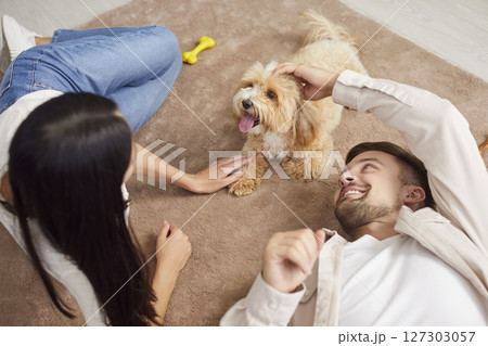 Young loving couple, happy family owners playing with cute pet puppy at home, spouses enjoy time 127303057